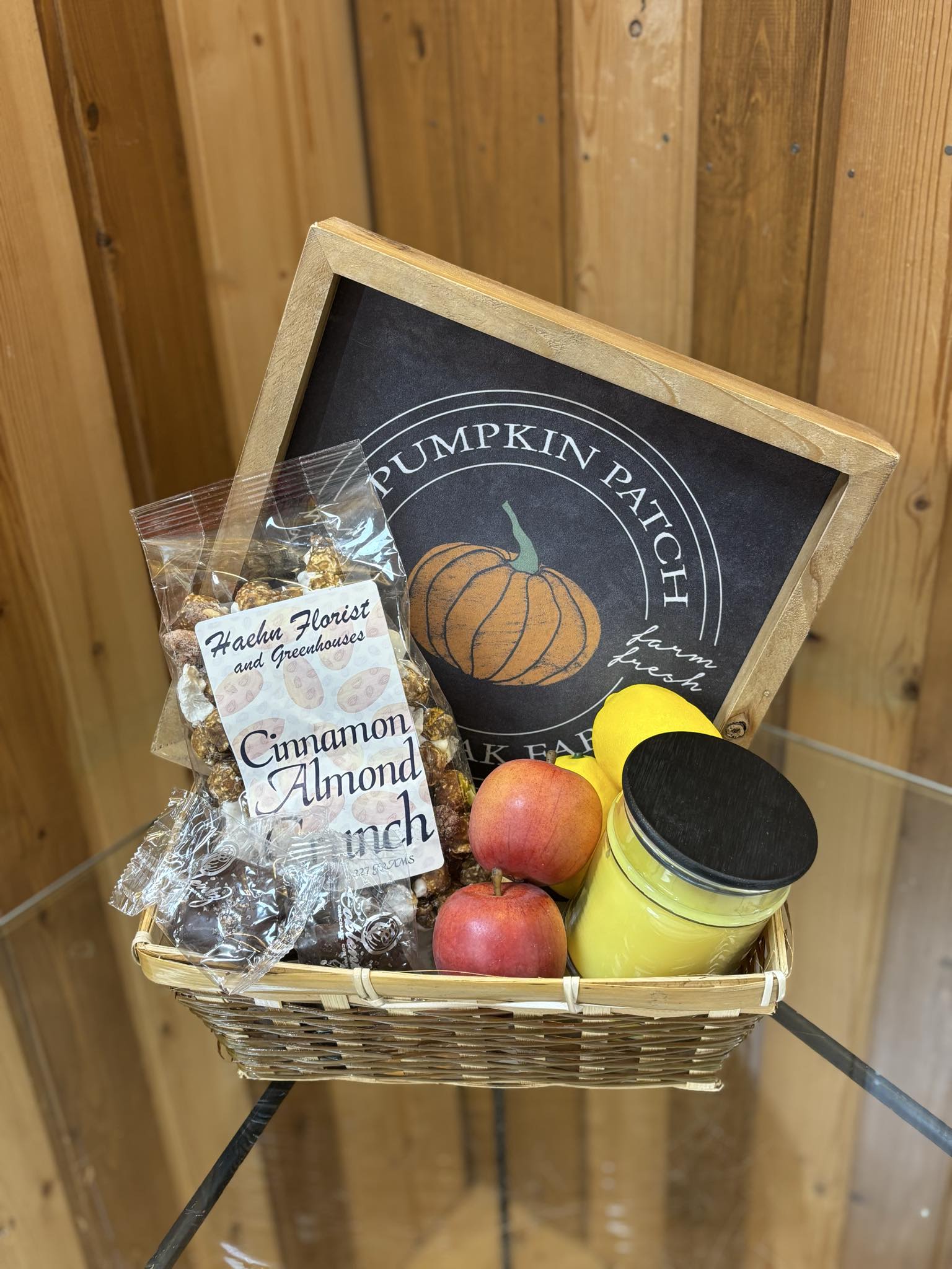 Basket of apples, candy, and a candle with a pumpkin patch sign