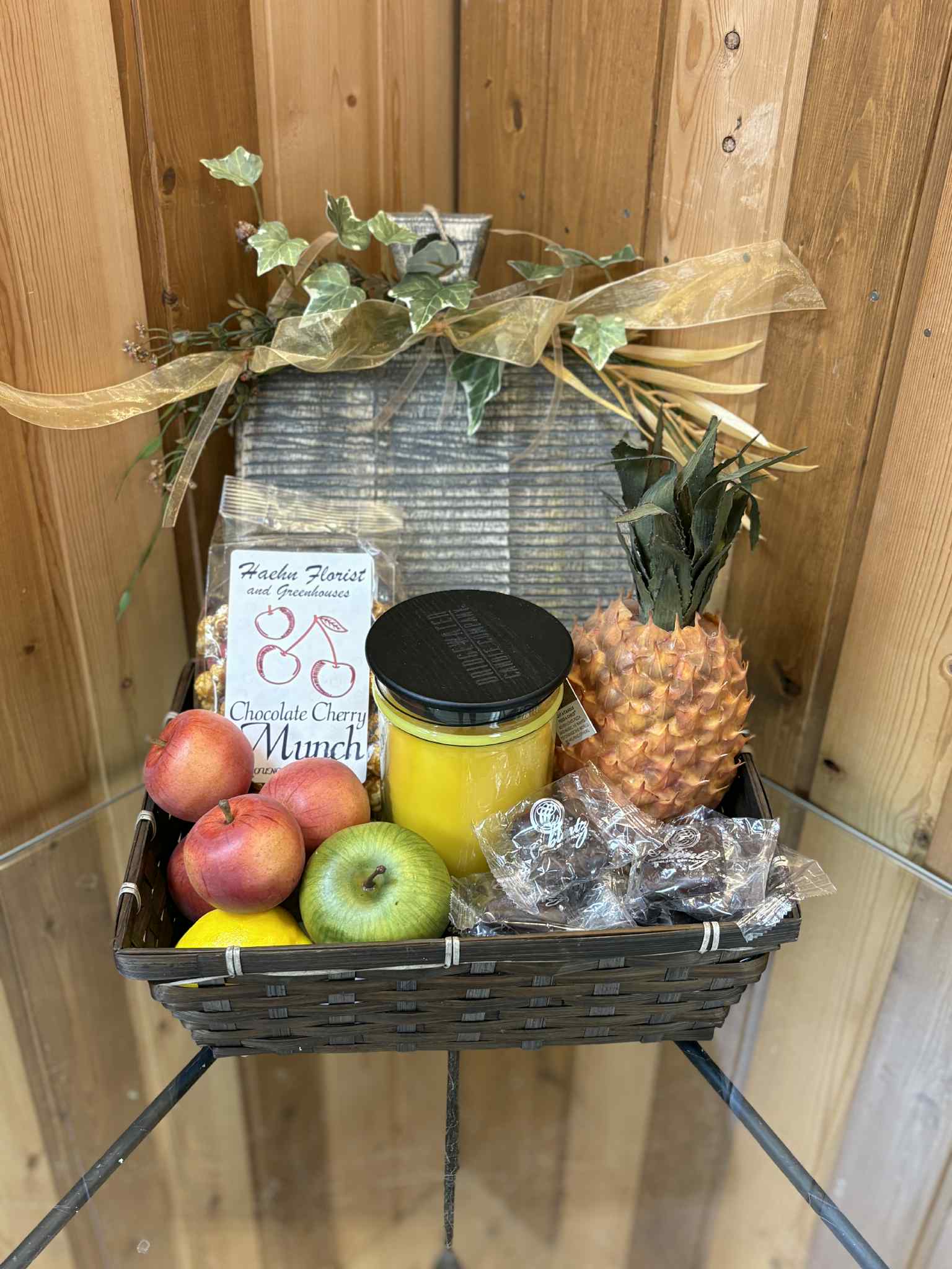 Fruit gift basket with pineapple, apples, peaches, candy, and a jar candle