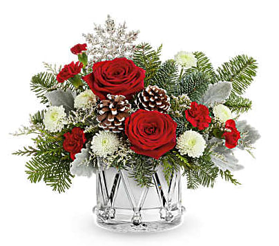 Red roses and white flowers in a clear glass vase with pinecones