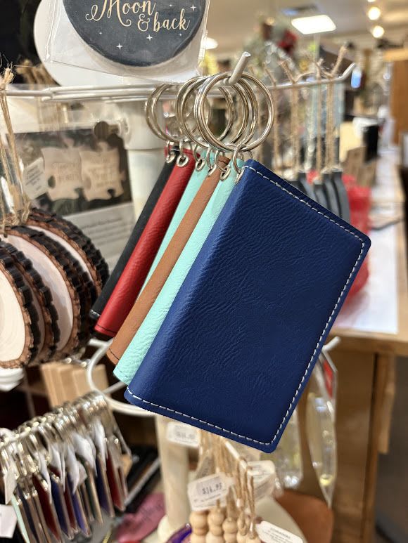 Leather keychain wallet cards hang on a display rack in a shop