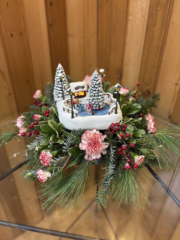 Winter floral arrangement with a miniature ice rink scene and pink flowers