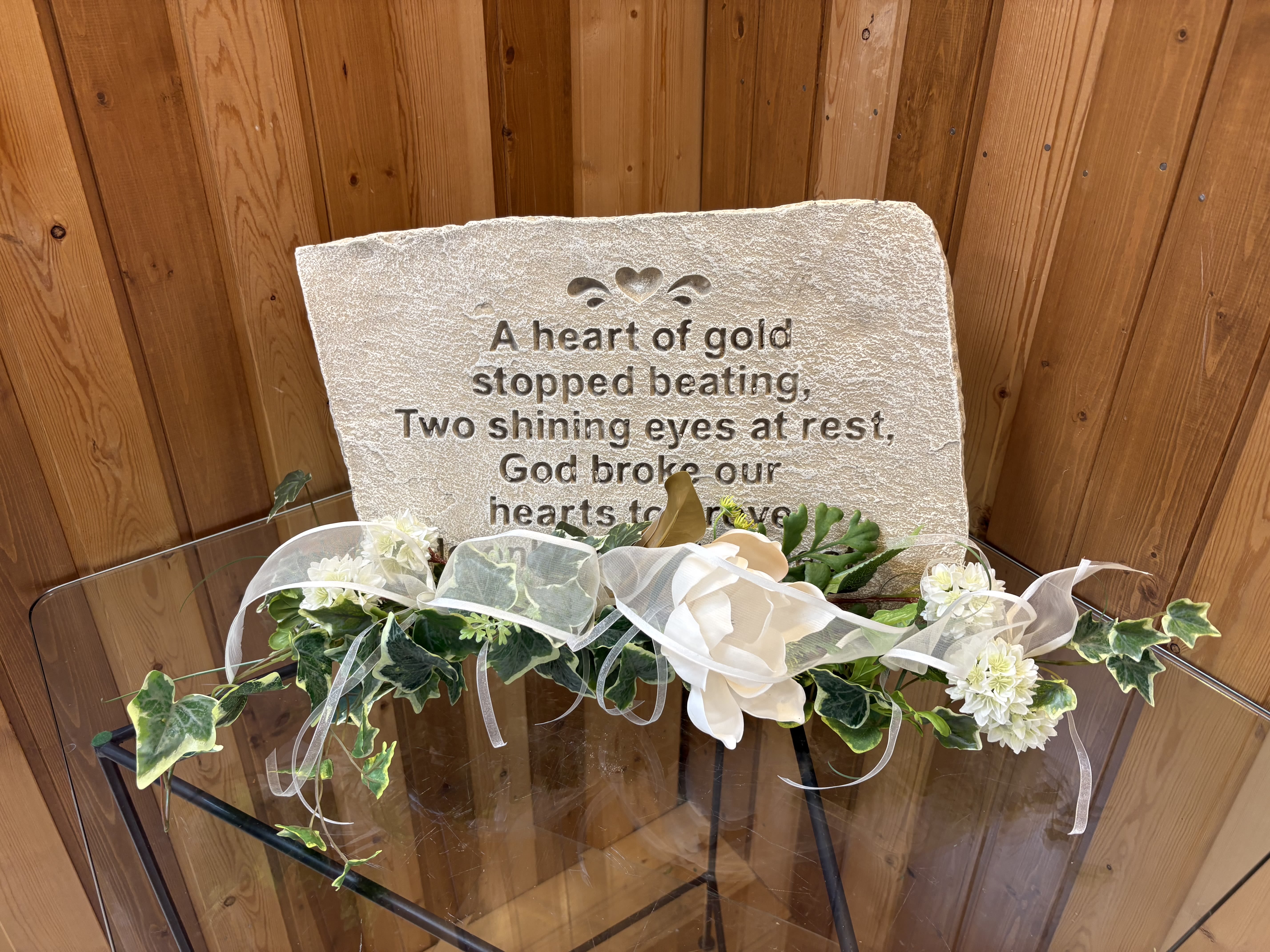 Memorial stone with white floral garland and ribbon
