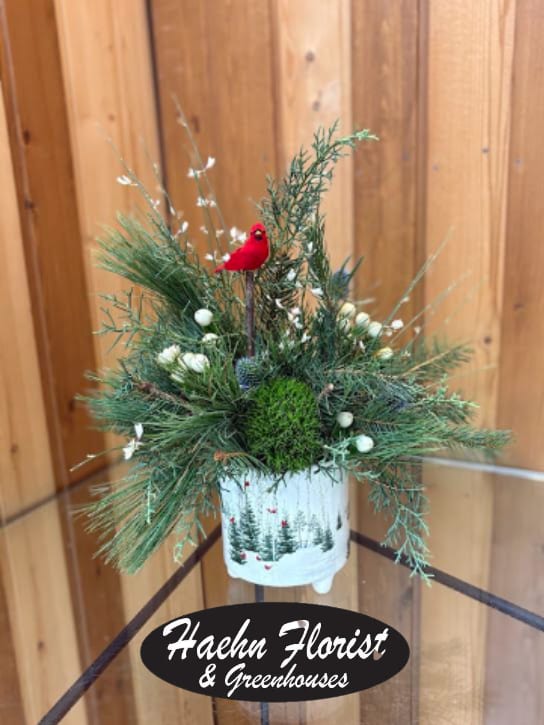 Holiday evergreen arrangement in a white container with a red bird ornament