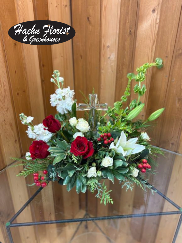 Red and white floral arrangement with a clear glass cross centerpiece