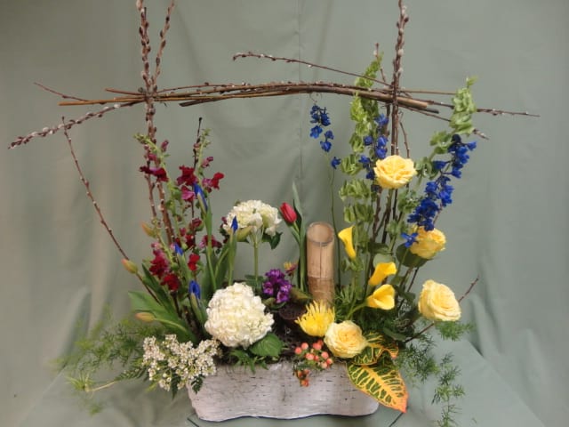 Mixed floral arrangement in a white rectangular container with tall branches