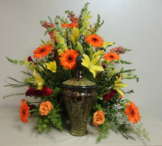 Orange gerbera daisies and yellow lilies in a decorative vase