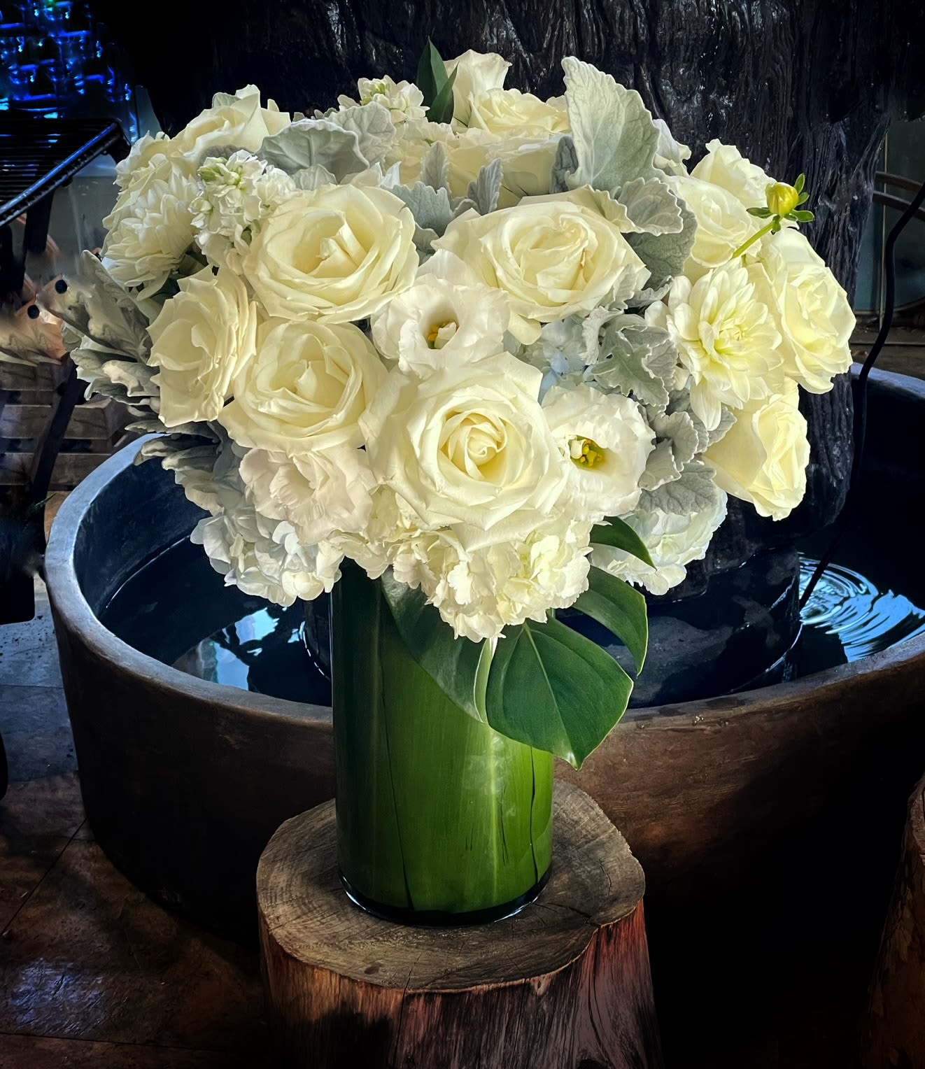 White roses and pale blooms arranged in a tall green vase
