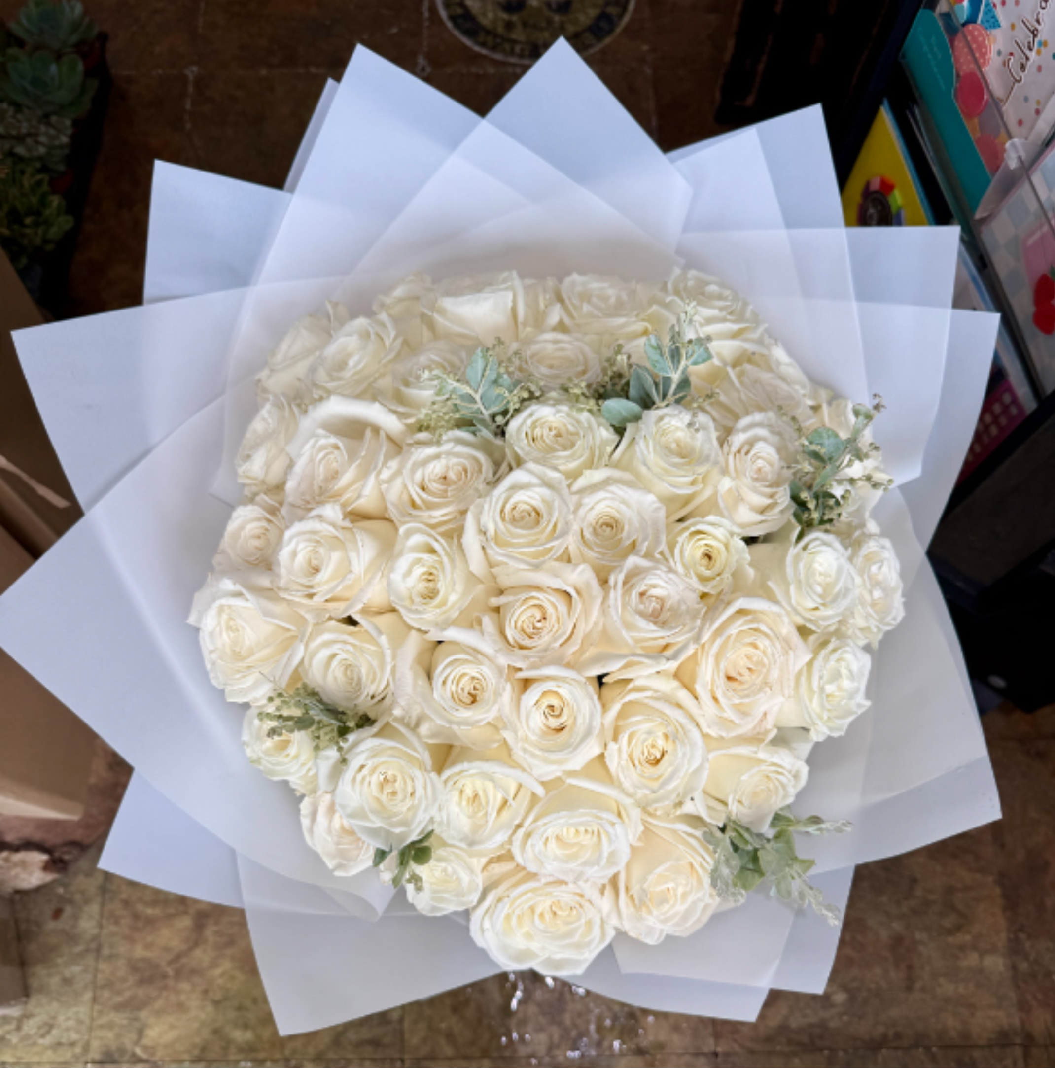 Pearl White Roses - This bouquet has a timeless, luxurious feel. An elegant gathering of pristine white roses, beautifully hand-wrapped in crisp white paper for a refined monochromatic presentation. Each rose is selected for its full, velvety bloom, creating a lush and abundant bouquet that symbolizes purity, grace, and everlasting love. A stunning expression of classic luxury, perfect for weddings, anniversaries, sympathy sentiments, or any occasion that calls for understated elegance. 