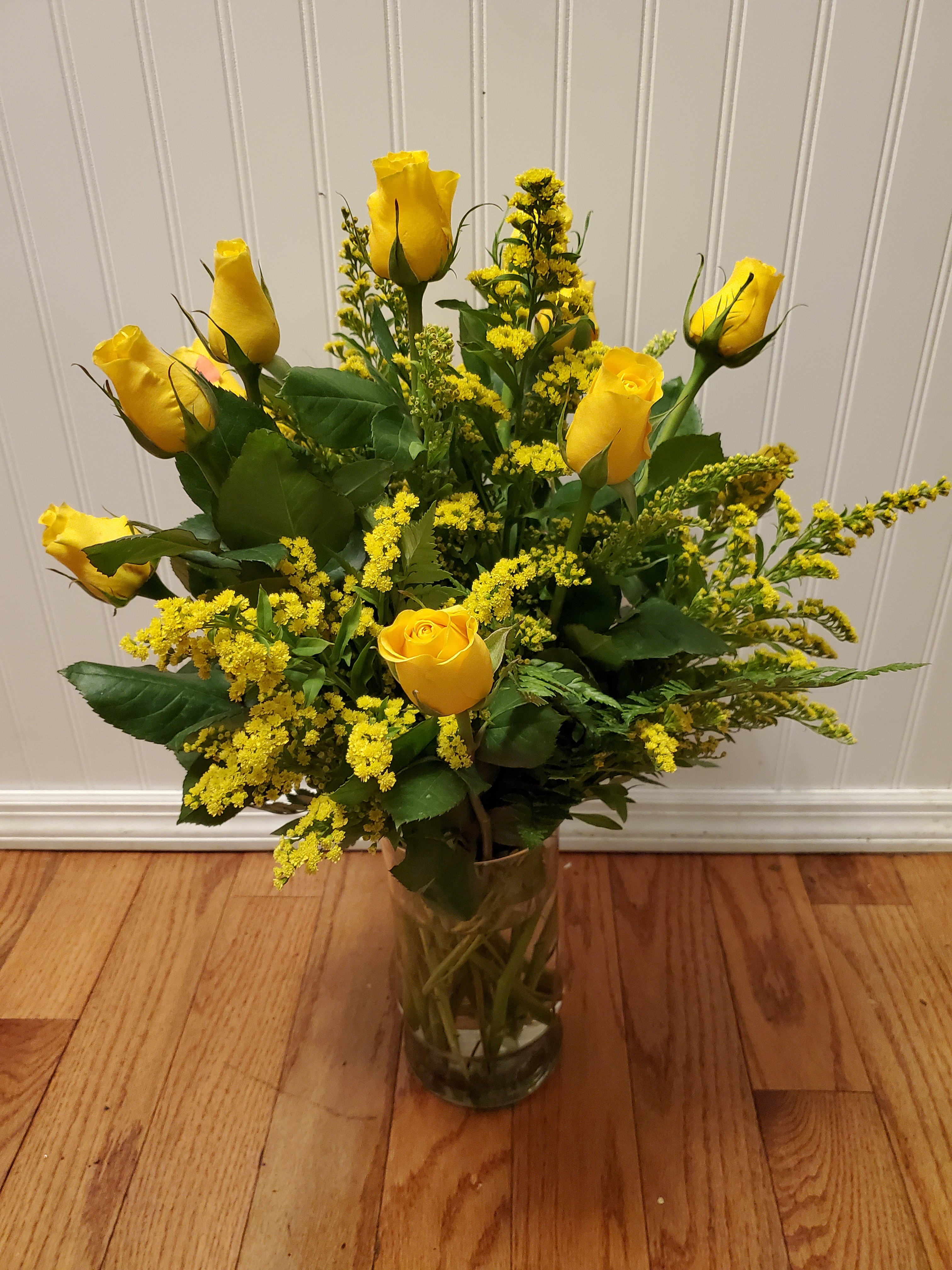 Tall arrangement of yellow roses with yellow filler in a clear glass vase