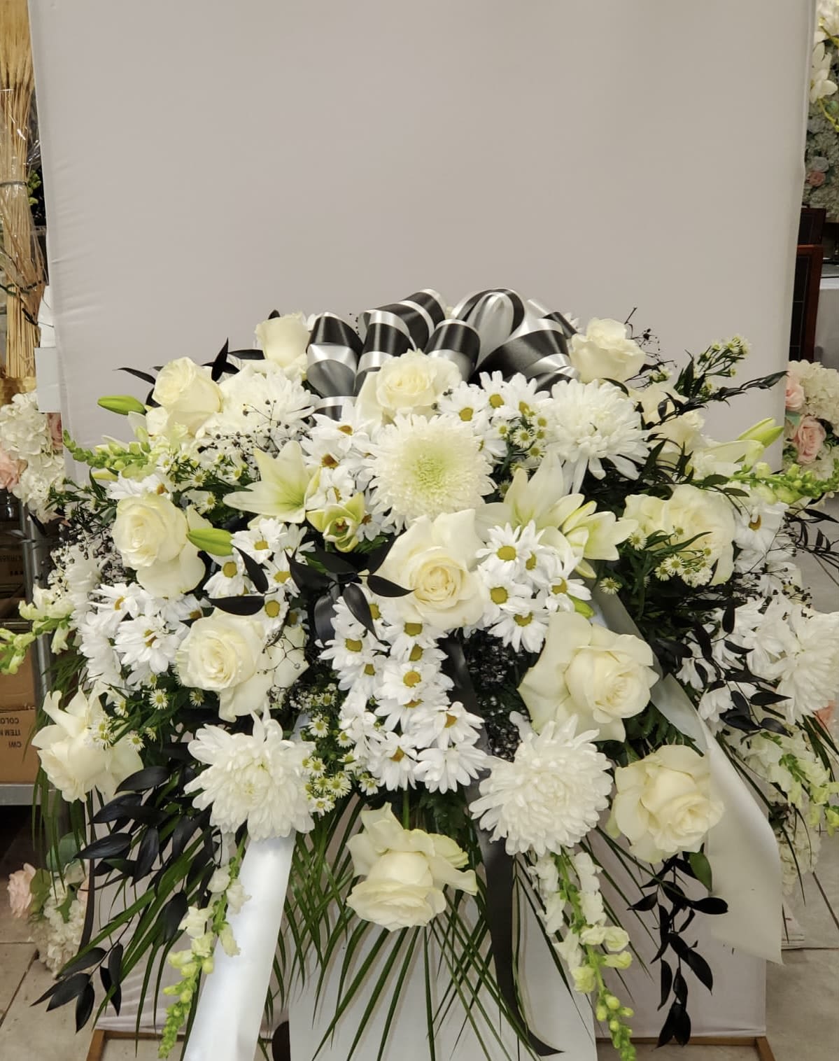 White floral funeral spray with roses, daisies, and lilies