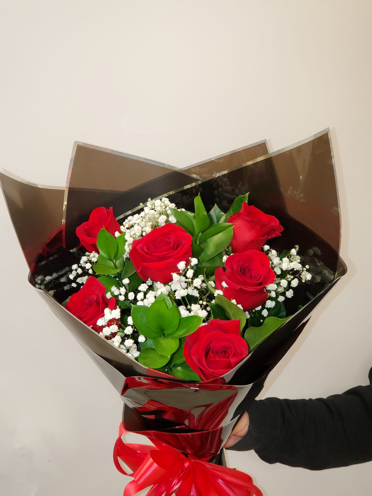 Bouquet of red roses with baby's breath wrapped in dark paper