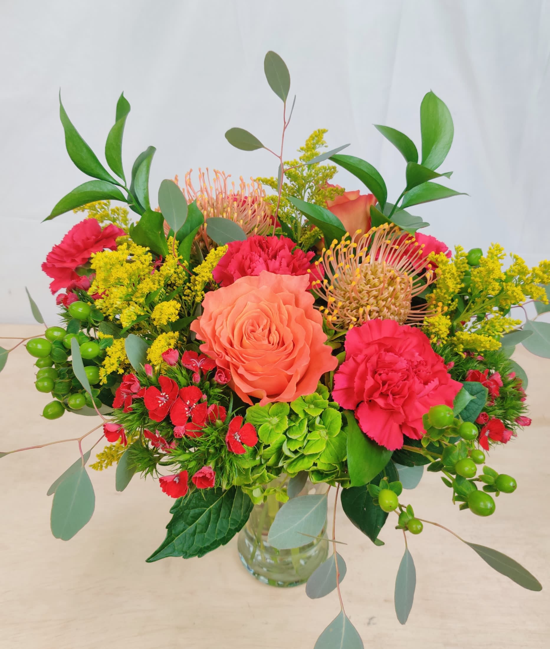 Mixed bouquet in a clear glass vase with coral roses and pink carnations
