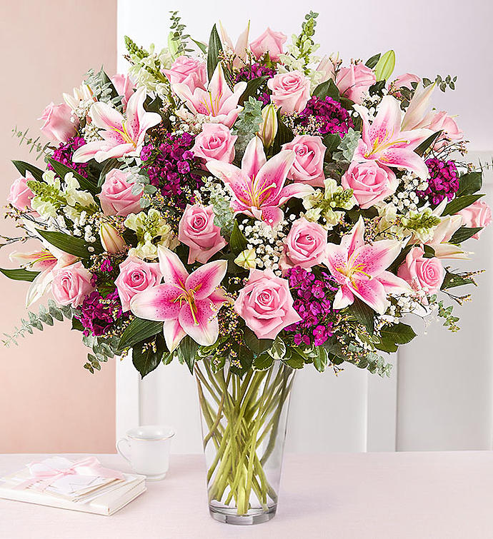 Pink roses and lilies arranged in a clear glass vase