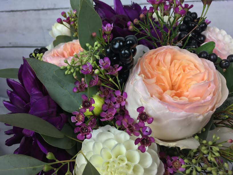 Peach and white roses with purple accent flowers in a bouquet