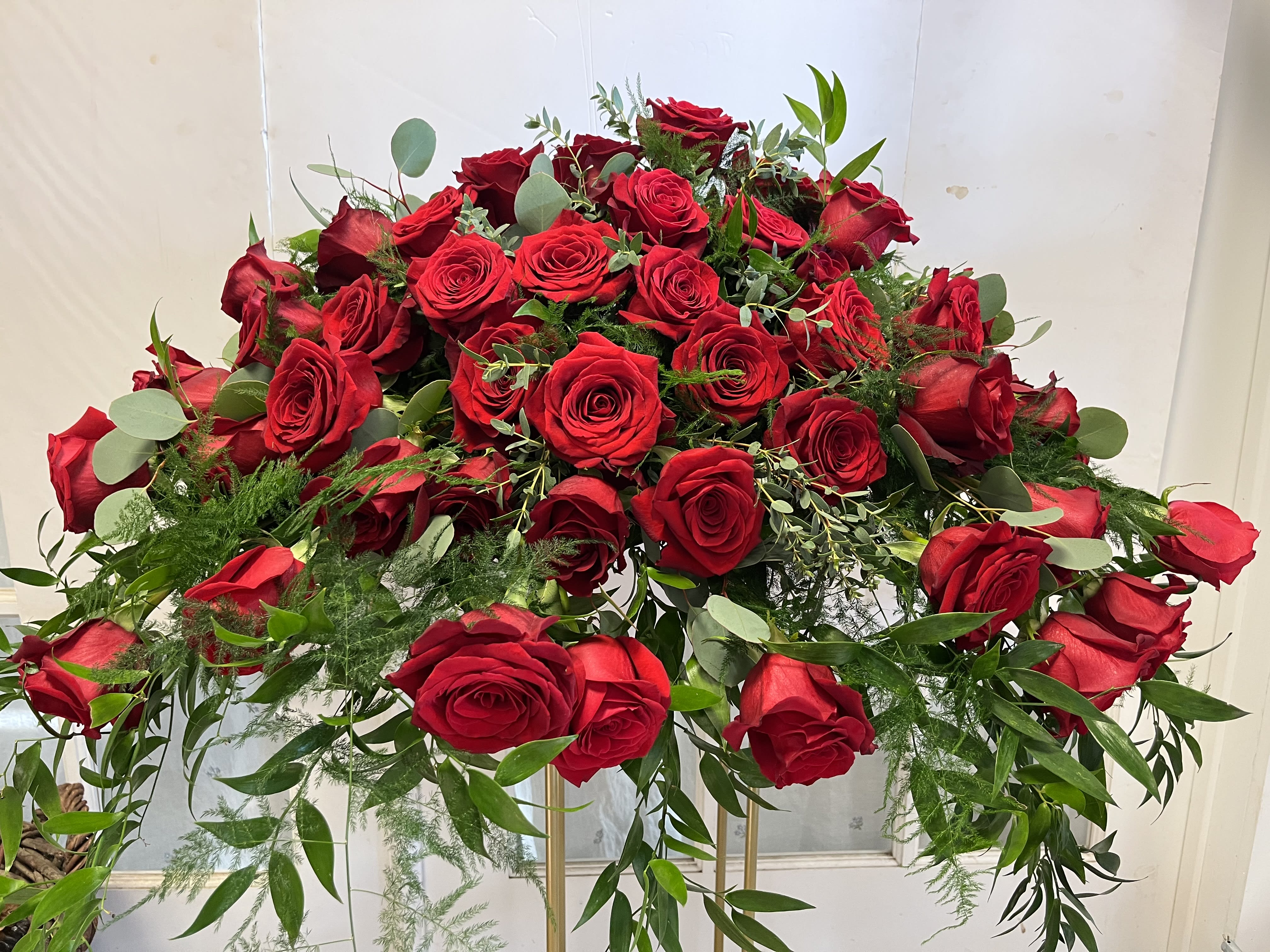 Large arrangement of red roses with greenery on a stand