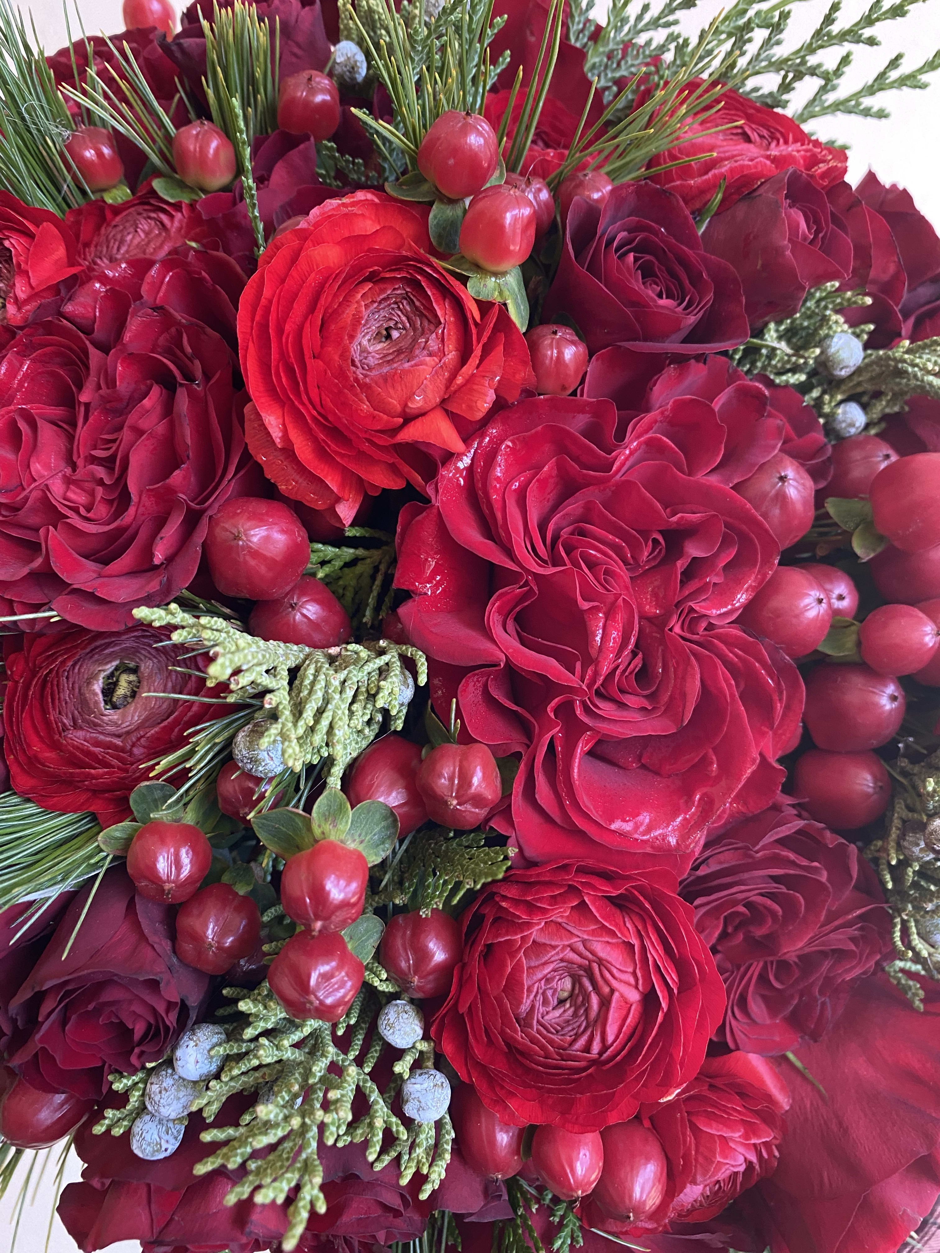 Close-up bouquet of red roses and ranunculus with berry accents