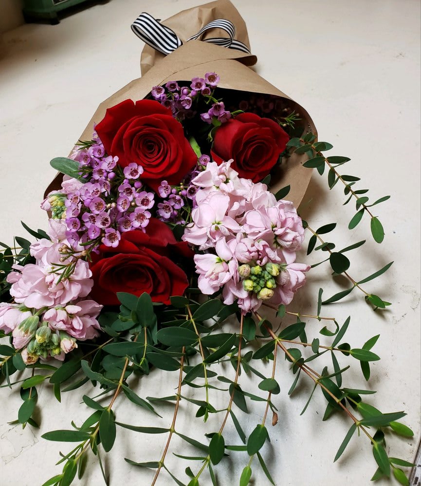Bouquet of red roses and pink flowers wrapped in brown paper