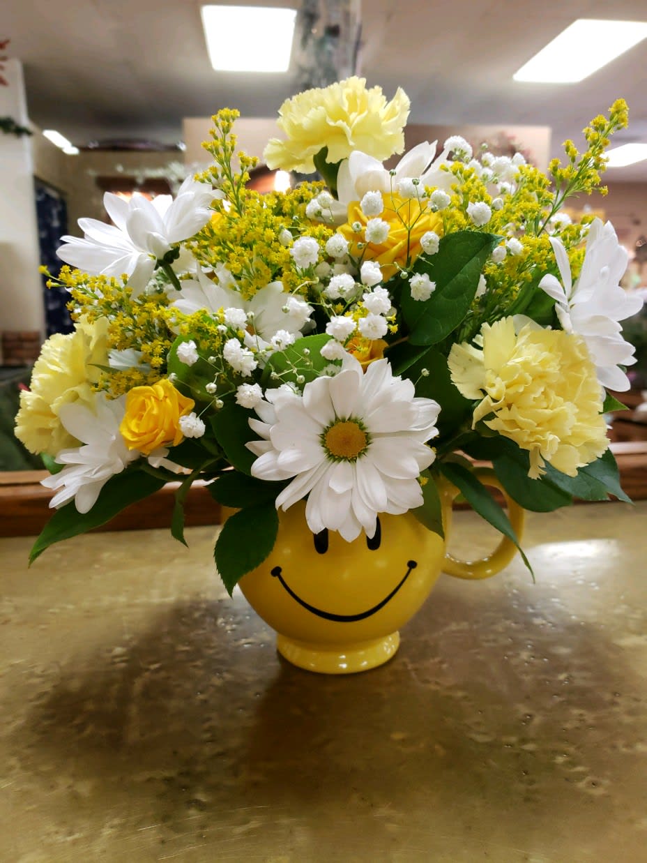 Yellow and white flower arrangement in a smiley-face mug