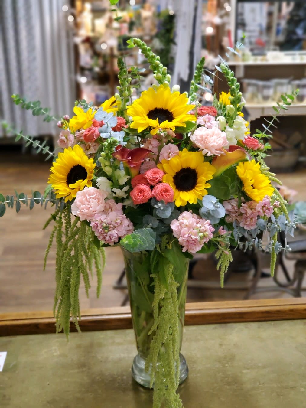 Tall mixed bouquet with sunflowers, pink blooms, and a glass vase