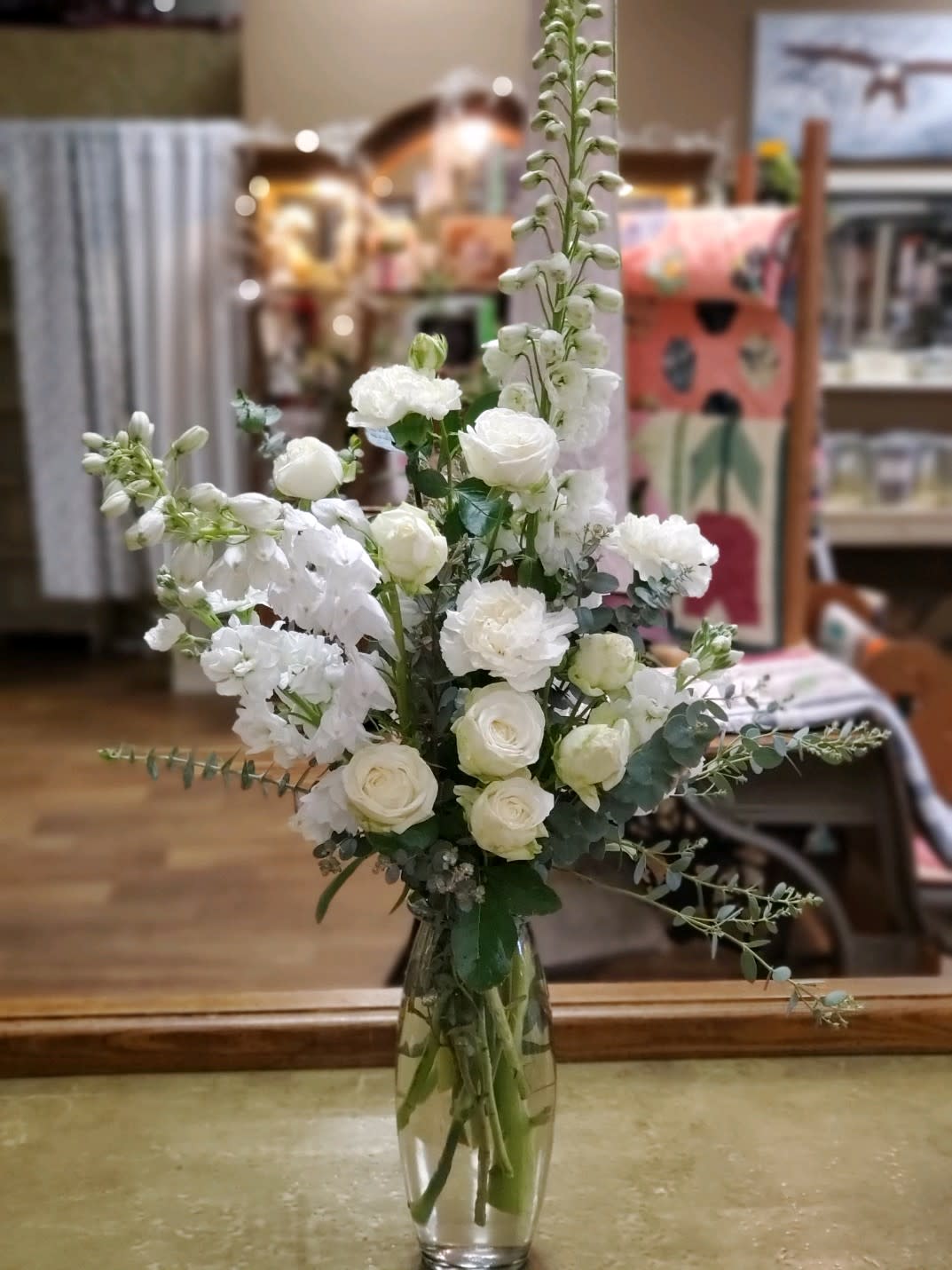 Tall white floral arrangement in a clear glass vase