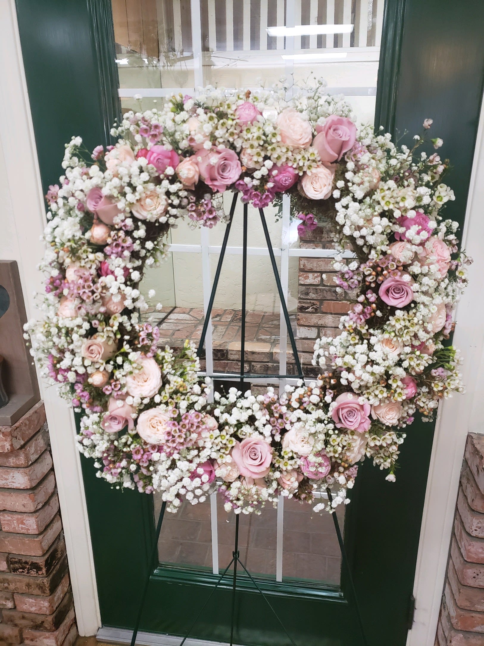 Heart-shaped floral wreath with pink roses and white baby's breath on an easel
