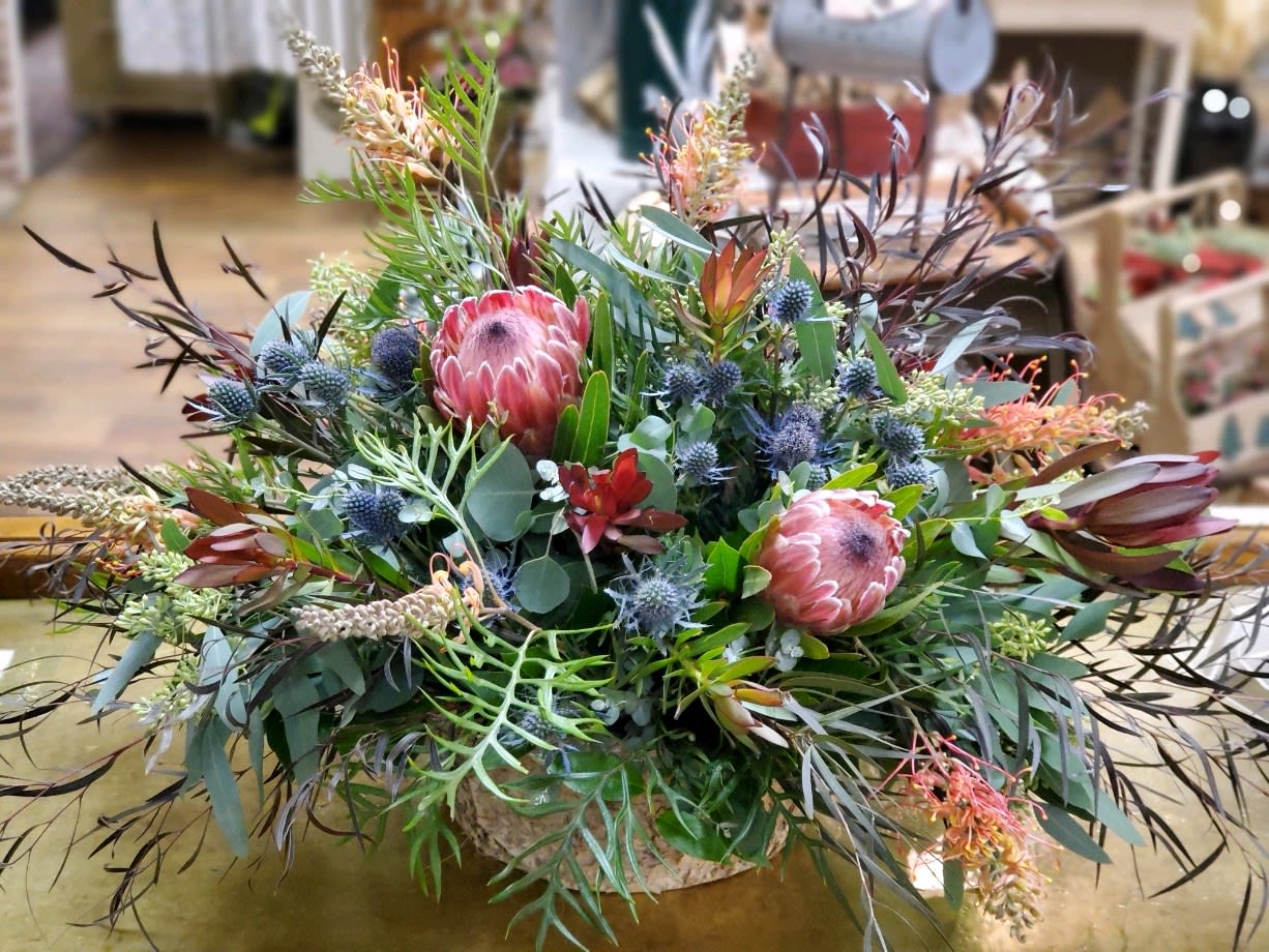 Large mixed floral arrangement with pink protea in a low container