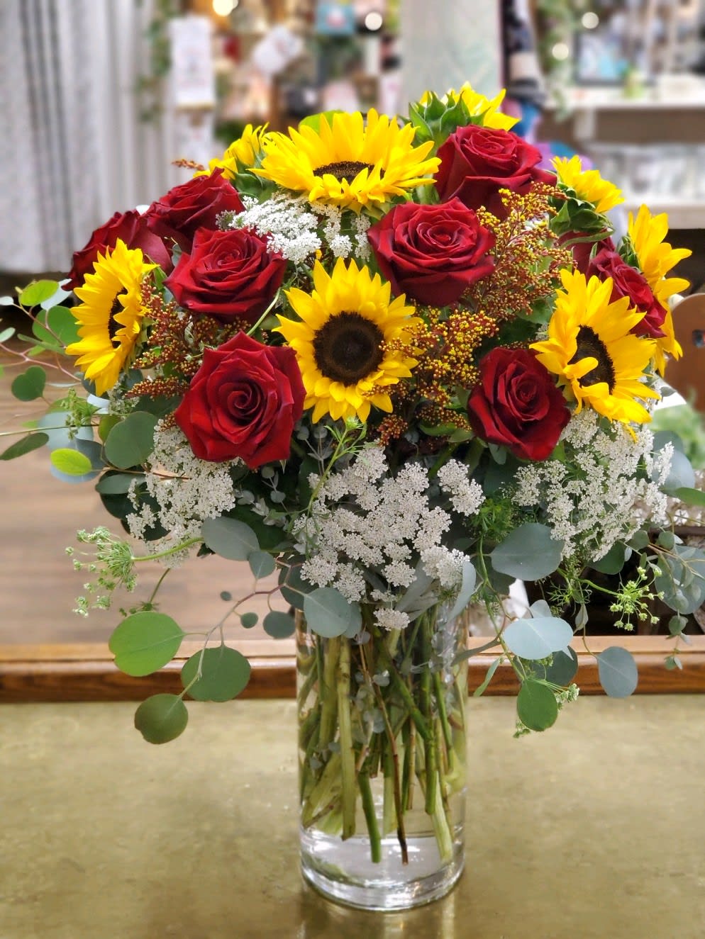 Bouquet of red roses and yellow sunflowers in a clear glass vase