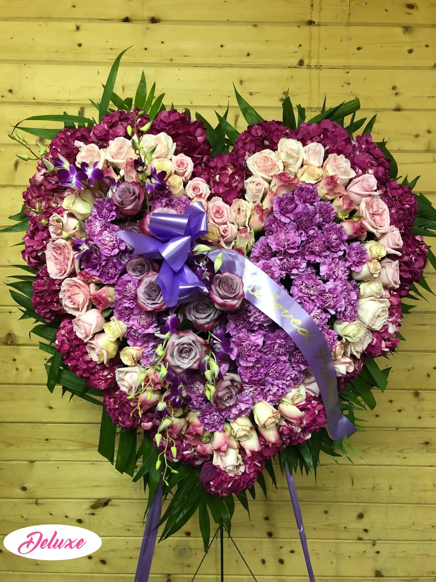 Heart-shaped floral tribute with pink and purple roses and hydrangeas