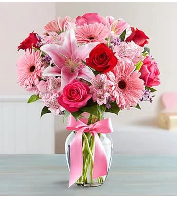 Pink and red mixed bouquet in a glass vase with a pink ribbon