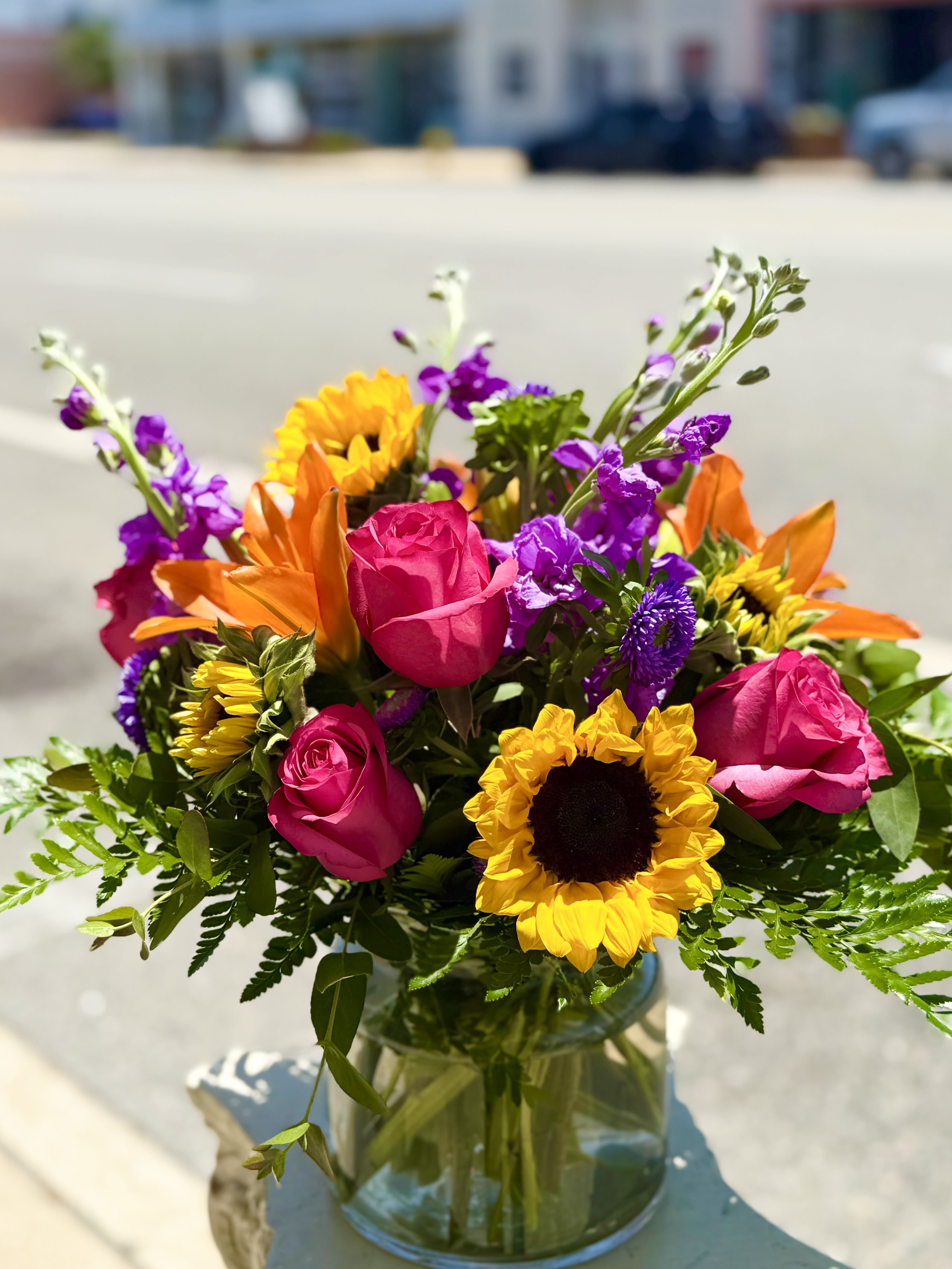 Bright mixed bouquet of roses and sunflowers in a glass vase