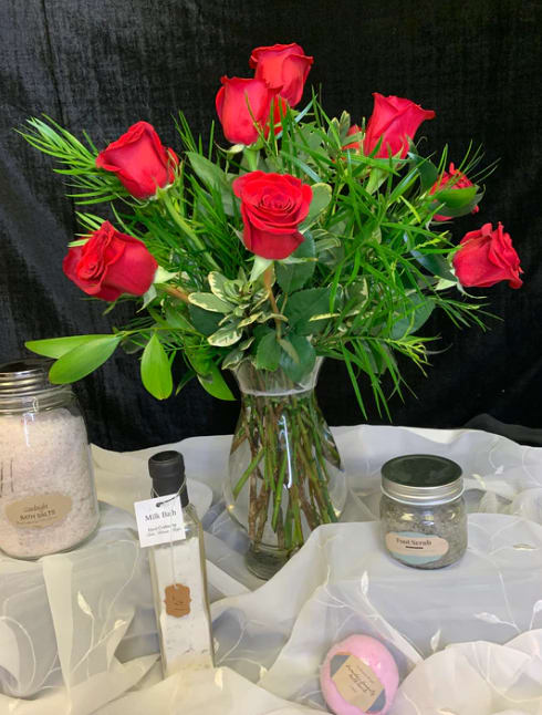 Red roses arranged in a clear glass vase with greenery
