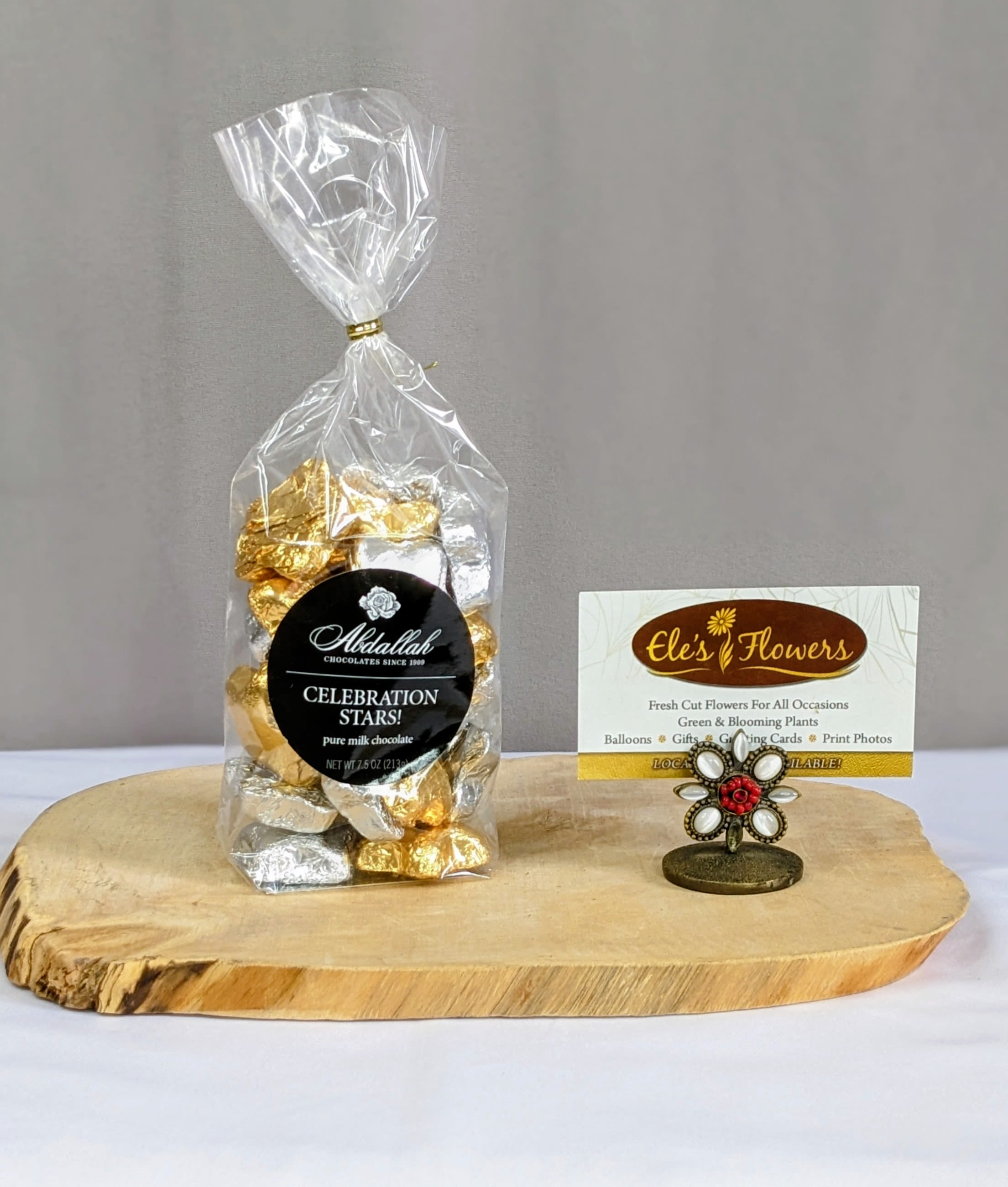 Bag of gold and silver wrapped chocolates with a business card holder on a wooden board