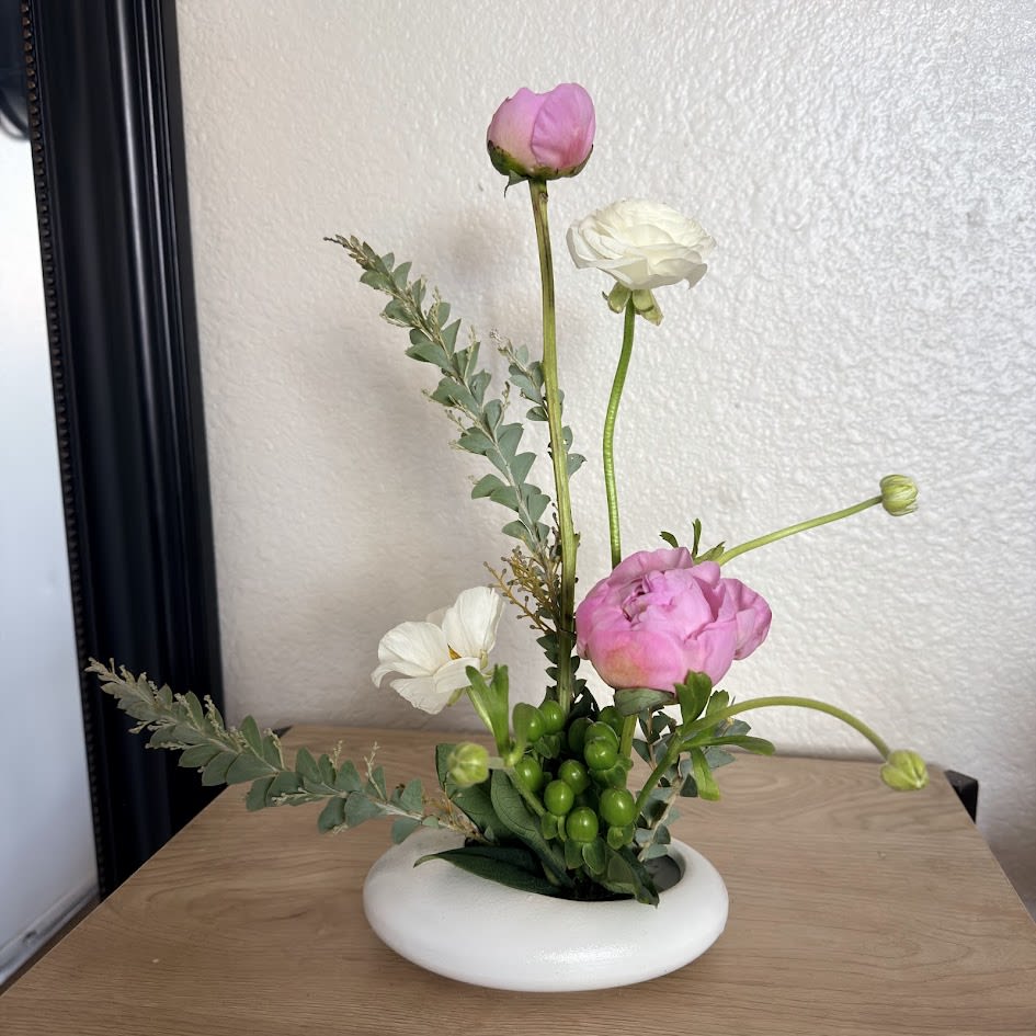 Peony Whisper Ikebana - A delicate and sophisticated ikebana arrangement designed to capture the essence of natural beauty in its purest form. Peony Whisper Ikebana blends the timeless elegance of peonies with a thoughtfully balanced composition that reflects harmony, flow, and serenity, inspired by the principles of Japanese floral art.  Each element is intentionally selected, focusing on form, space, and texture to create a design that conveys calmness and refinement. Its minimalist and organic aesthetic makes it a perfect piece for both modern and classic spaces, adding a touch of distinction while preserving the natural beauty of the flowers.  This arrangement is ideal for celebrating special moments, expressing sincere emotions, or simply elevating any environment with an elegant, soft, and deeply contemplative style.