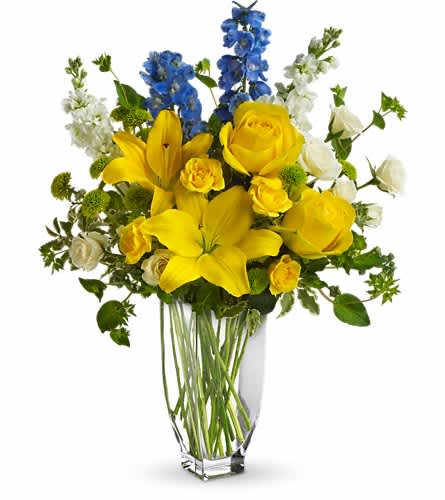 Yellow lilies and roses with blue and white flowers in a clear vase