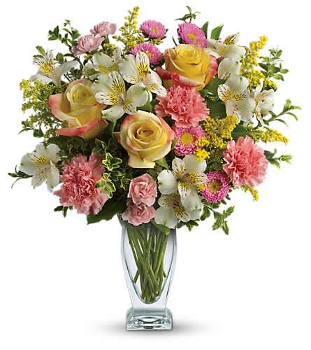Bouquet of yellow roses, pink carnations, and white alstroemeria in a clear glass vase