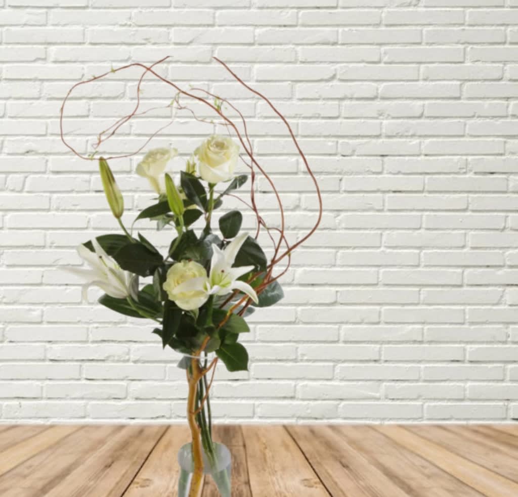 Tall bouquet of white roses and lilies in a clear vase