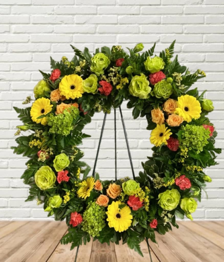 Floral wreath with yellow gerbera daisies, green blooms, and peach roses