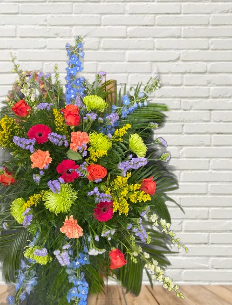Large mixed floral spray with roses, gerbera daisies, and blue delphinium