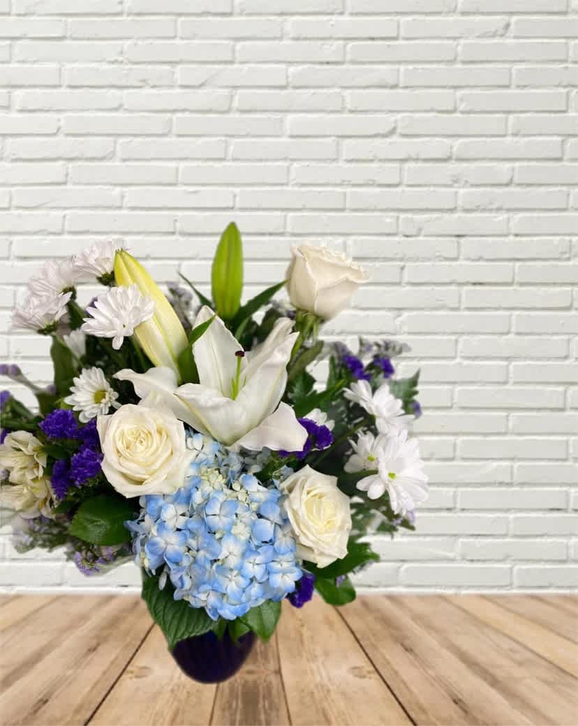 White lilies, roses, and blue hydrangea in a vase