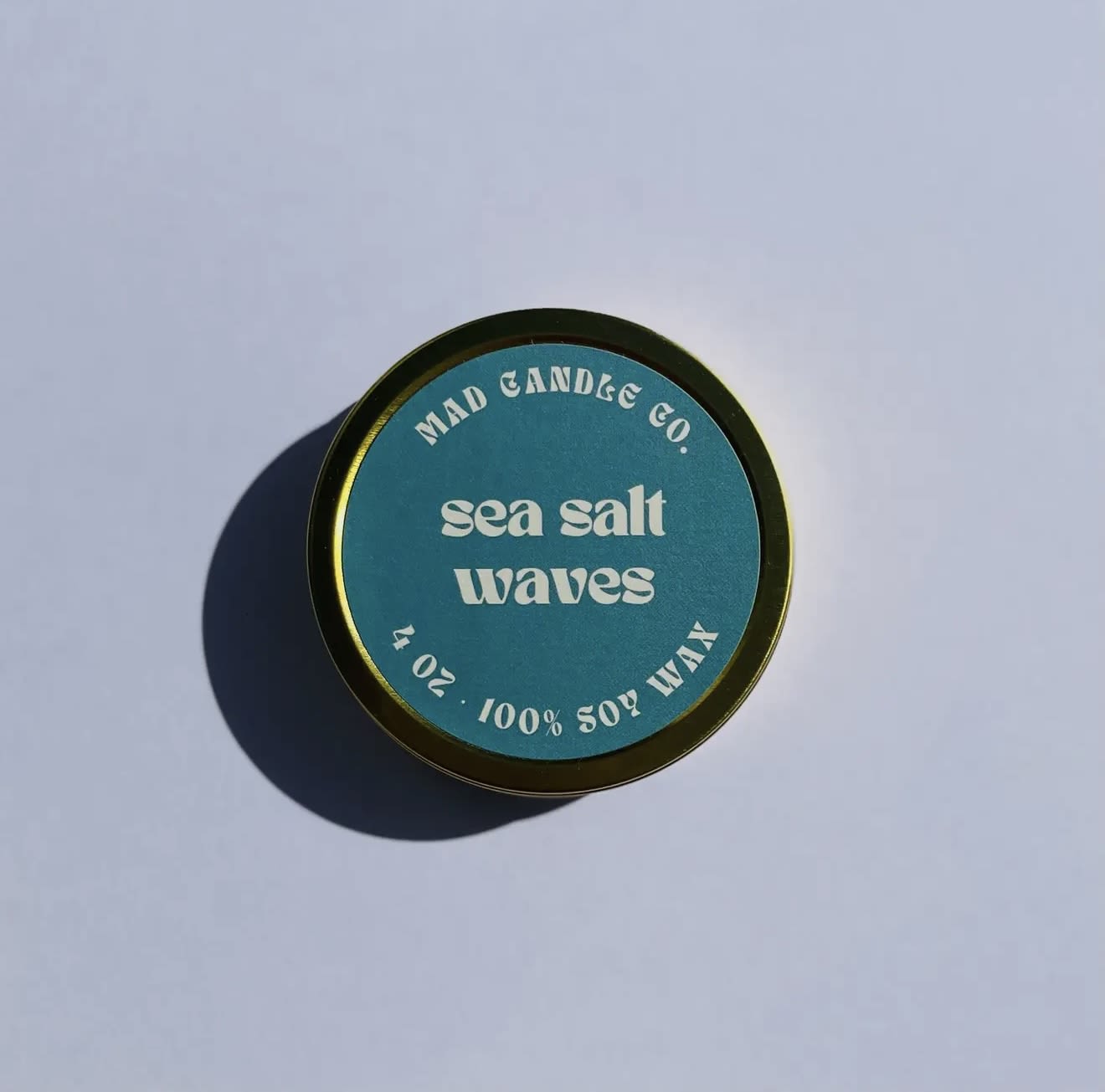 Round candle tin labeled "sea salt waves"