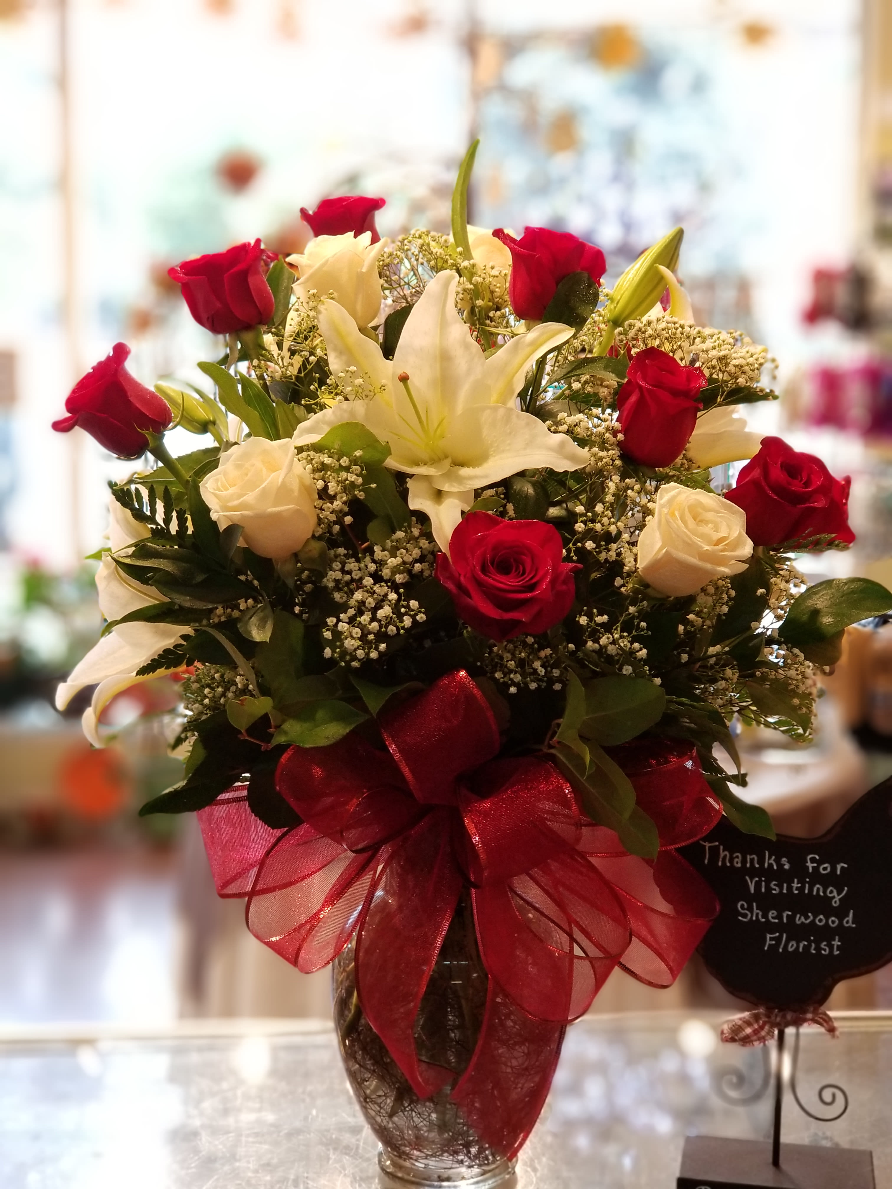 Bouquet of red and white roses with a white lily in a glass vase