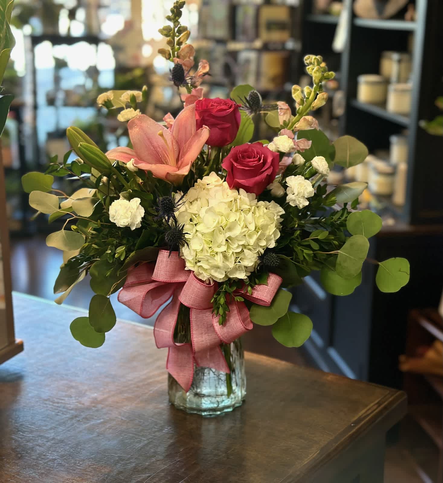 Pink roses and lilies in a glass vase with a pink ribbon