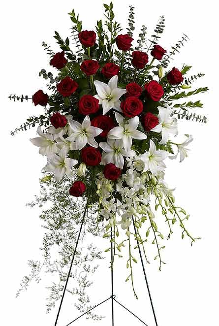Standing floral spray with red roses and white lilies on a black easel