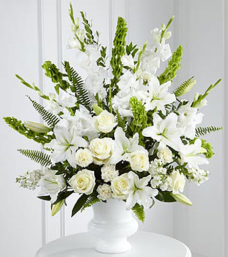 White floral arrangement in a white vase with tall green accents