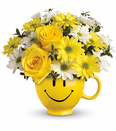 Yellow roses and daisies arranged in a smiley-face mug
