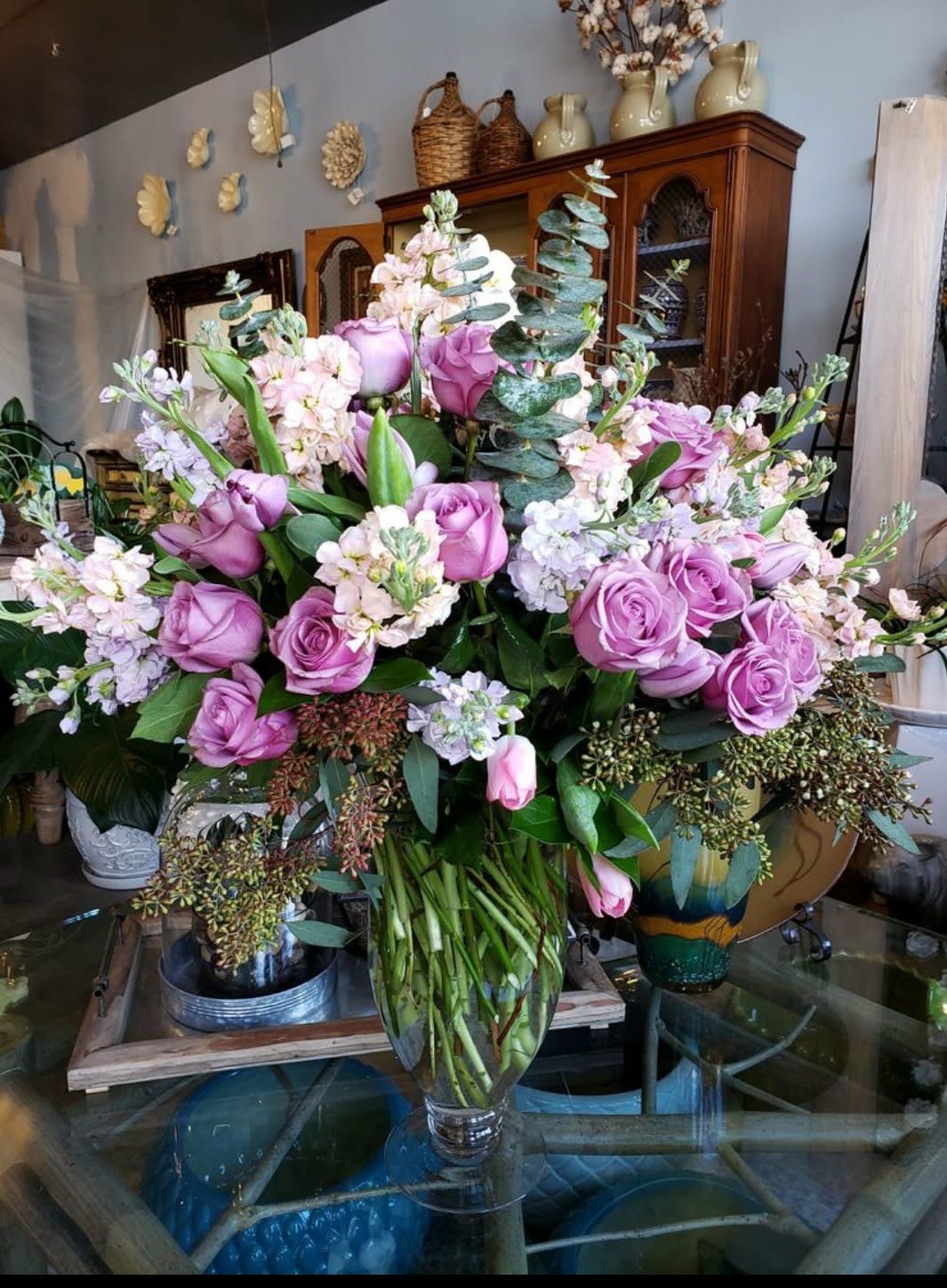 Lavender roses and pale pink flowers arranged in a clear glass vase