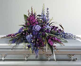 Purple floral casket spray with blue accents on a silver casket