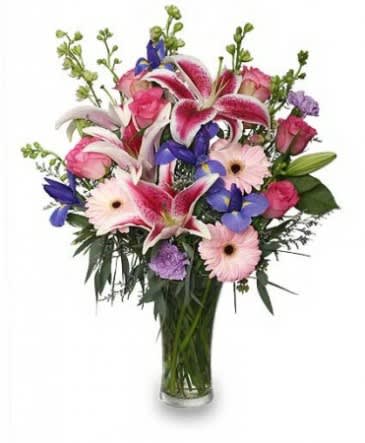 Mixed bouquet of pink lilies, roses, and gerbera daisies in a glass vase