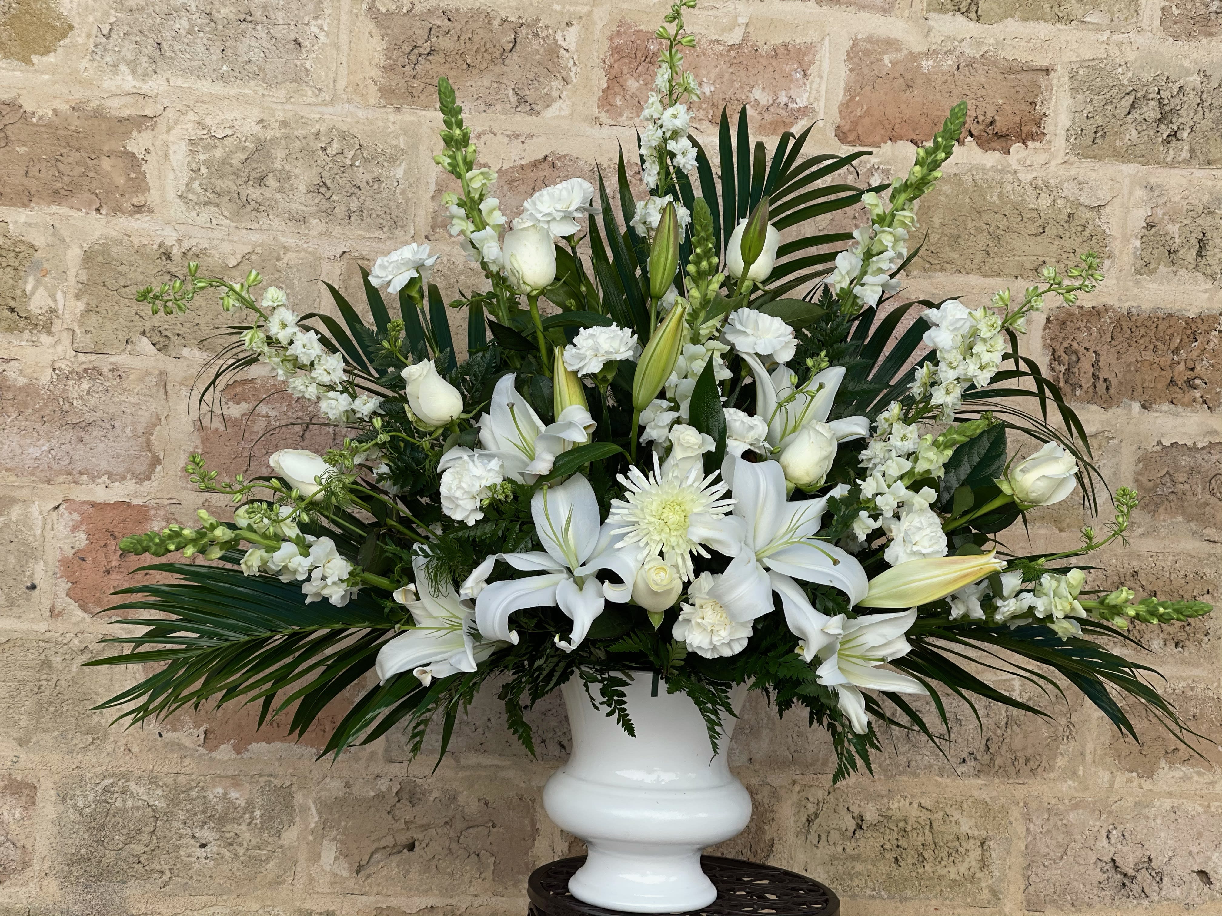 White lilies and roses arranged in a white urn vase