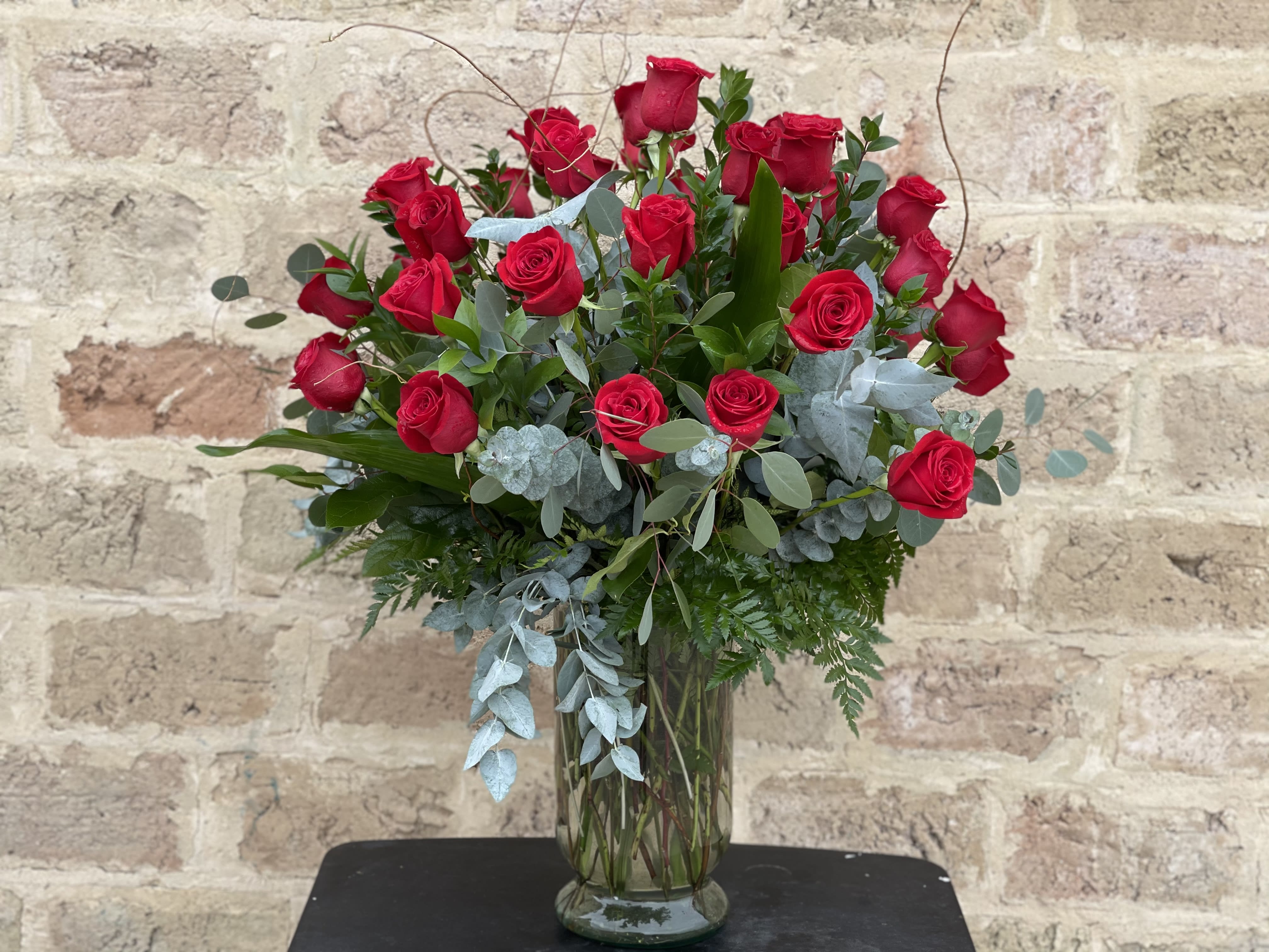Tall arrangement of red roses in a clear glass vase